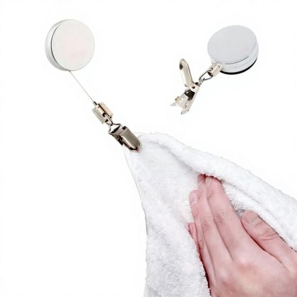 Retractable adhesive towel rack holding a white towel with metal clip and circular mount.