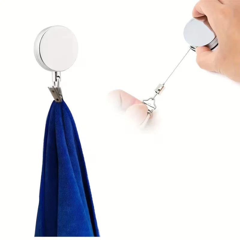 Retractable adhesive towel rack holding a blue towel on a bathroom wall.